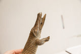 Close-up of African crocodile sculpture, showing textured head, open mouth, and aged scales.
