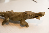 Carved details of the crocodile's textured head, showing the fish held in its open jaw.