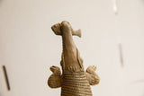 Upward view of the handmade crocodile sculpture's textured head and fish.