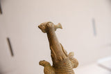 Upward view of the vintage crocodile sculpture's head holding a fish in its mouth.