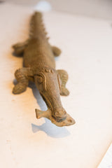 Close view of the aged patina on the crocodile sculpture's head holding a fish.