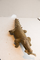 Low-angle view of the vintage African crocodile sculpture, showing its textured scales and long body.