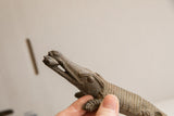 The vintage crocodile sculpture's head and open jaw, revealing a fish held within.