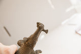 Upward view of the vintage African crocodile's carved snout holding a fish.