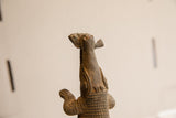 View from below of the vintage African crocodile sculpture holding a fish in its mouth.