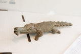 Side profile of a vintage hand-carved crocodile sculpture showing its textured body.