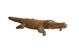 Vintage African crocodile sculpture with a carved scale texture holding a fish in its mouth.