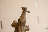 Upward detail view of the vintage crocodile sculpture holding a fish in its jaws.