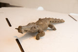 Three-quarter profile of the vintage African crocodile with fish sculpture.