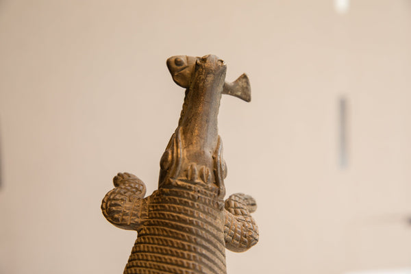 Upward view of the vintage crocodile sculpture's head holding a fish.