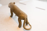 Rear view of the vintage cheetah sculpture, showing its textured back and curled tail.