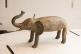 Profile view of a vintage African elephant sculpture with a weathered, textured surface.