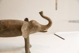 Profile view of a vintage elephant sculpture highlighting its textured, aged patina.
