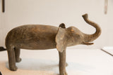 Vintage elephant sculpture in profile, highlighting its handmade, rustic texture.