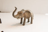 Profile view of a vintage elephant sculpture with a rustic, textured surface.