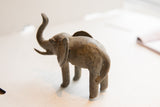 Rear view of a vintage African elephant sculpture, showing its textured form and raised trunk.