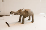 Side profile of a vintage African elephant sculpture showing its aged, textured surface.