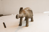 Close-up view of the vintage elephant sculpture's head and curled trunk, showing its handmade texture.