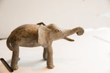 Side profile of a vintage handmade elephant sculpture with a rustic, mottled patina.