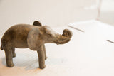 Side profile of the vintage elephant sculpture highlighting its aged, handmade texture.
