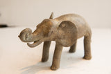 Angled view of a vintage handmade elephant sculpture showing its weathered, rustic texture.