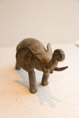 The expressive, textured face of a vintage African elephant sculpture viewed from the front.
