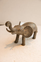 Profile view of a vintage elephant sculpture showing its handmade, rustic character.