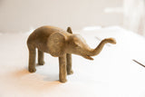 Angled profile of the vintage elephant sculpture showing its earthy, textured finish.