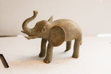 Three-quarter view of the handmade vintage elephant sculpture, showing its earthy, textured patina.