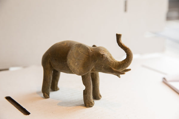 Three-quarter view of a vintage elephant sculpture with a matte, earth-toned texture.