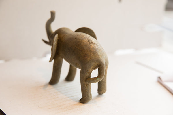 Rear view of the vintage African elephant sculpture highlighting its textured surface and curved tail.