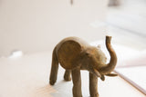 Face of a vintage African elephant sculpture with a textured patina and raised trunk.