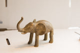 Profile of a vintage African elephant sculpture with a rustic, handmade-looking finish.