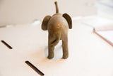 Vintage African elephant sculpture viewed from the back, showing its tail and weathered surface.