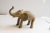 Three-quarter view of a vintage elephant sculpture showing its aged, handmade finish.