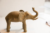 Profile view of the vintage elephant sculpture highlighting its rustic texture and raised trunk.