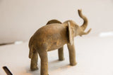 Vintage elephant sculpture seen from the back, showing its textured, aged finish.