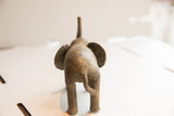 Vintage elephant sculpture viewed from behind, showing its textured body and tail.