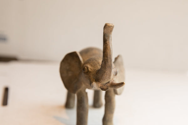 Frontal view of a handmade elephant sculpture, highlighting its textured face and raised trunk.