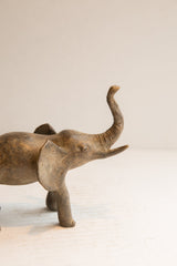Profile view of the vintage African elephant showing its weathered texture and raised trunk.