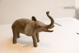 Angled side profile of the vintage elephant sculpture's textured body and raised trunk.