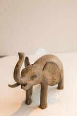 Angled view of a vintage elephant sculpture's textured head with trunk raised.