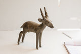 Side profile of the vintage antelope sculpture showing its handmade form and textured, aged surface.