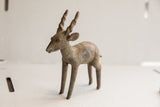 Profile view of a vintage African antelope sculpture with an aged, earthen texture.