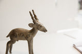 Profile view of a vintage antelope sculpture highlighting its aged patina and handmade form.
