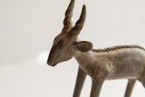 Close-up of the vintage antelope sculpture's head, highlighting its rustic texture and twisted horns.