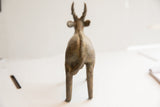 Vintage African antelope sculpture viewed from behind, showing its carved spine and tail.
