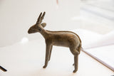 Vintage African antelope sculpture in profile, showing its textured back and slender legs.