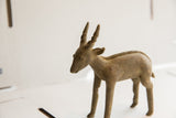 Side profile of a vintage antelope sculpture showing its textured horns and braided spinal detail.