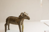 Vintage African ram sculpture profile, detailing the curled horns and weathered surface.